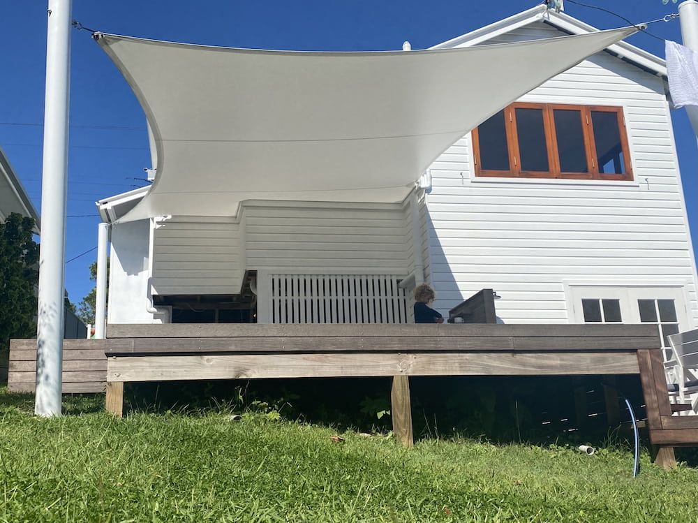 A White House With A Wooden Deck And A Shade Sail — SPF Shades and Sails in Ballina, NSW