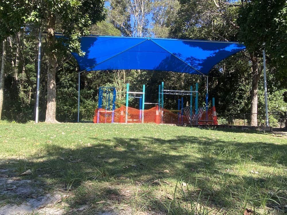 A Blue Umbrella Is Covering A Playground In A Park — SPF Shades and Sails in Tweed Heads West, NSW