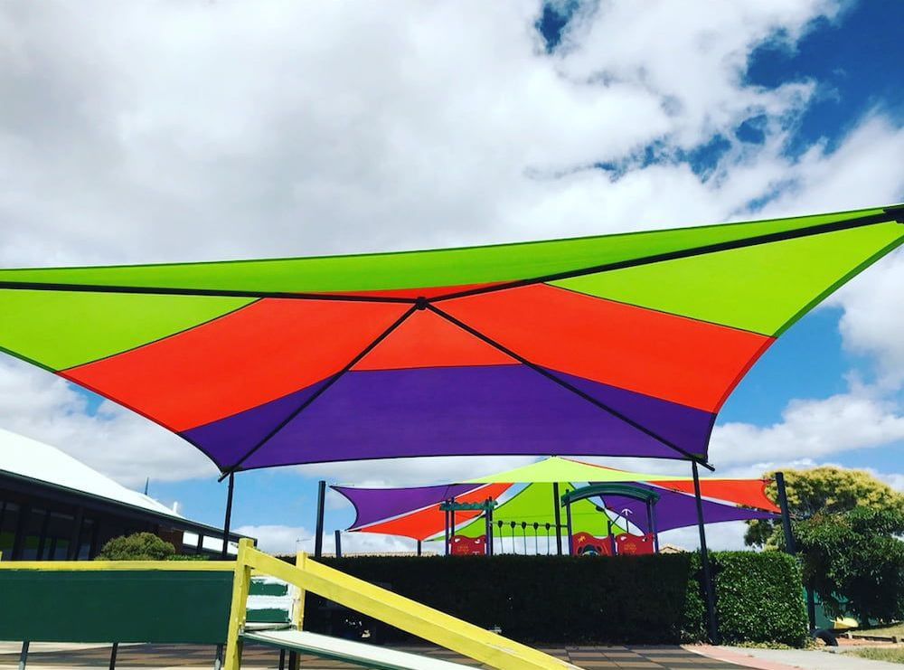 A Colourful Umbrella Is Sitting In Front Of A Playground — SPF Shades and Sails in Tweed Heads West, NSW