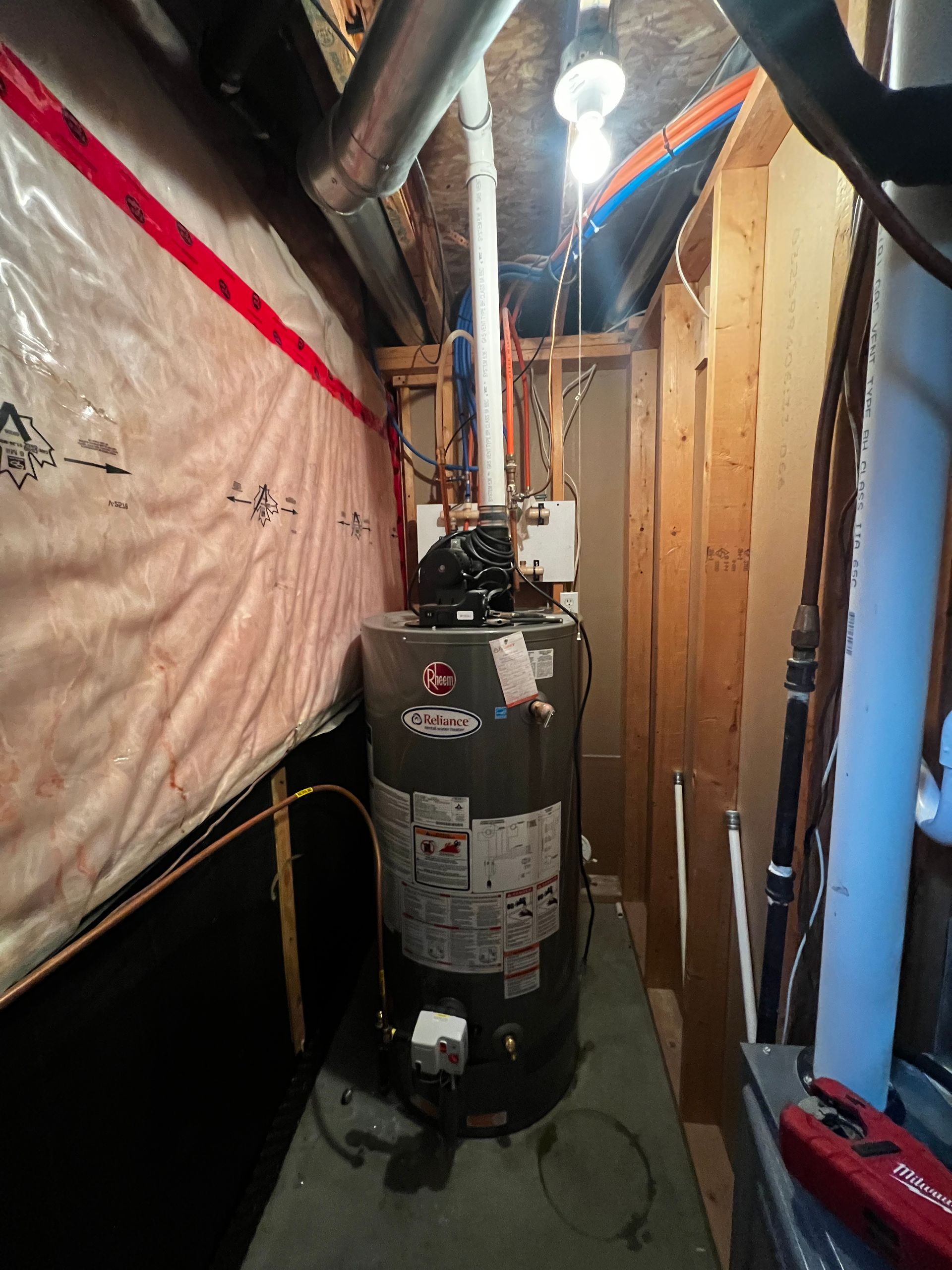 A water heater is sitting in the corner of a room in a basement.