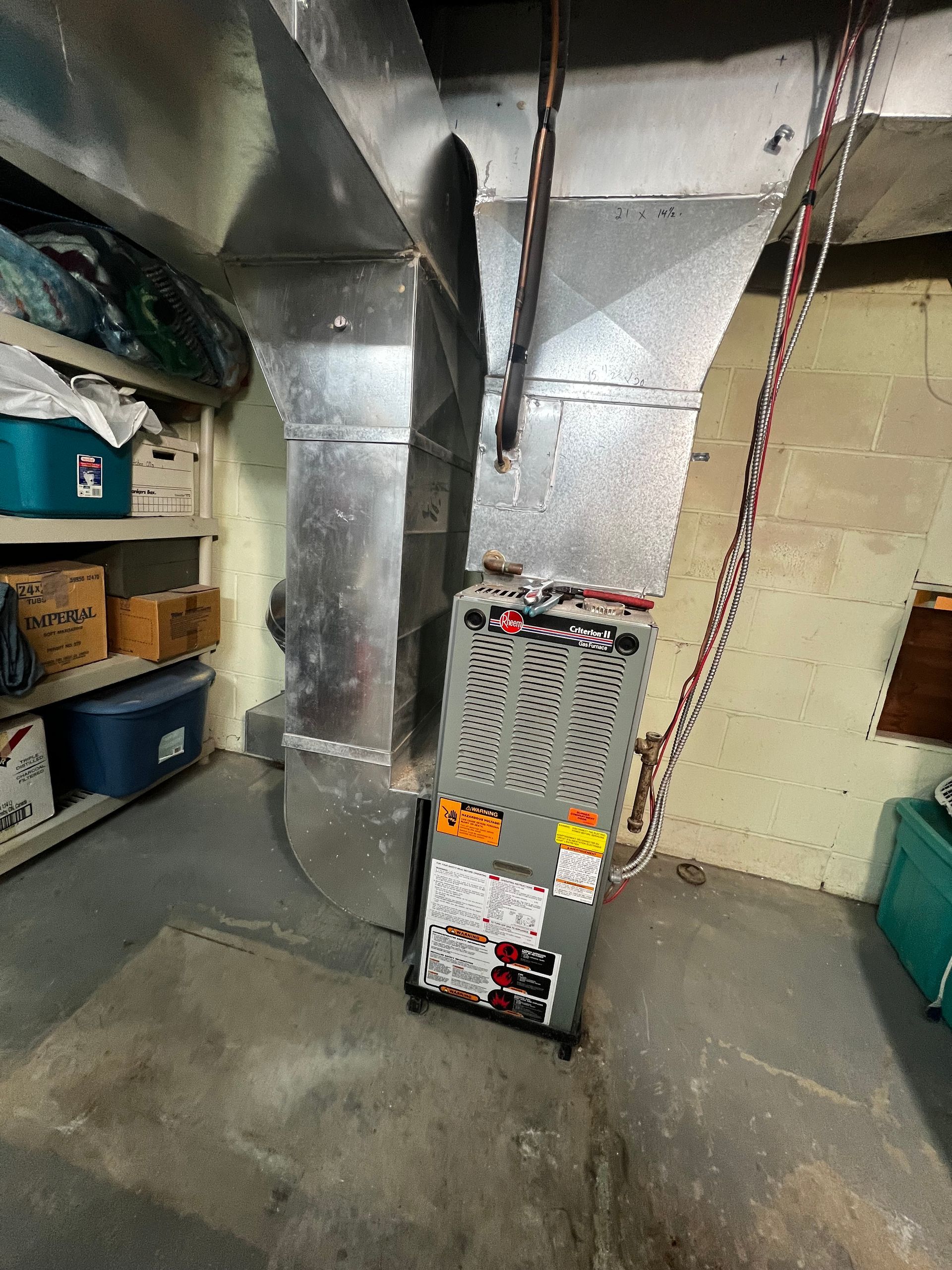 An air conditioner is sitting in a basement next to a staircase.