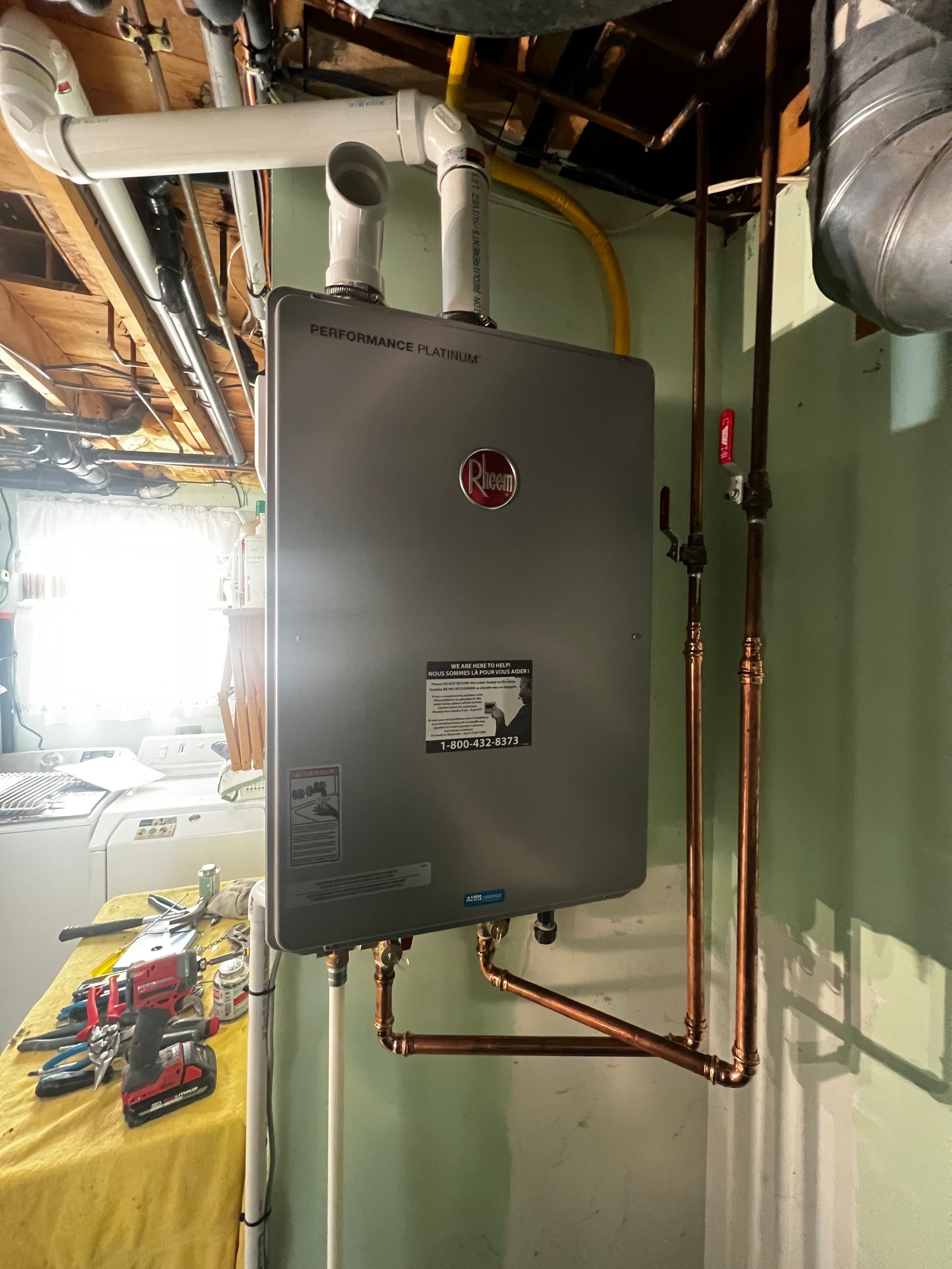 A water heater is hanging from the ceiling in a basement.