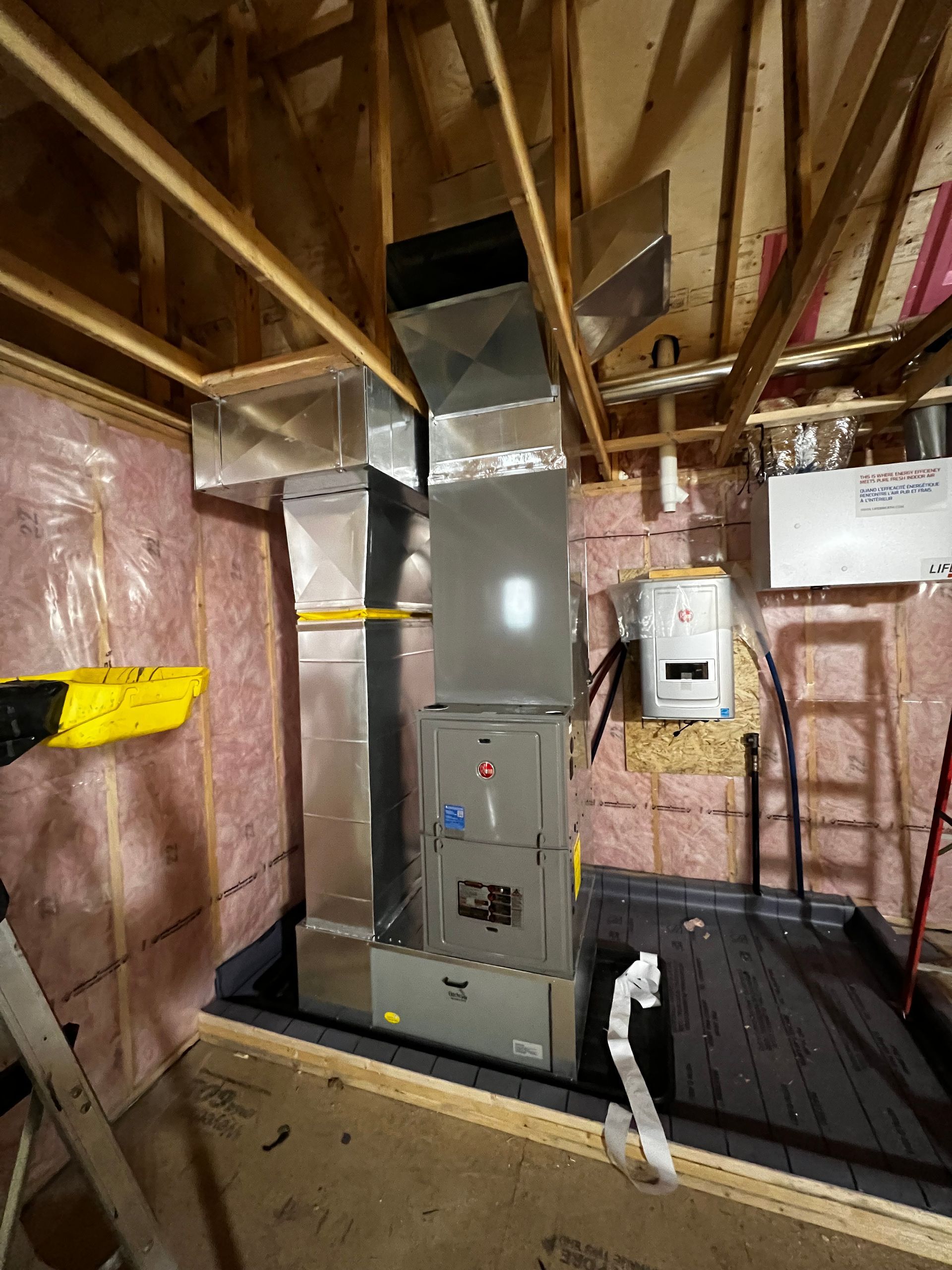 A person is working on a heating system in a room under construction.