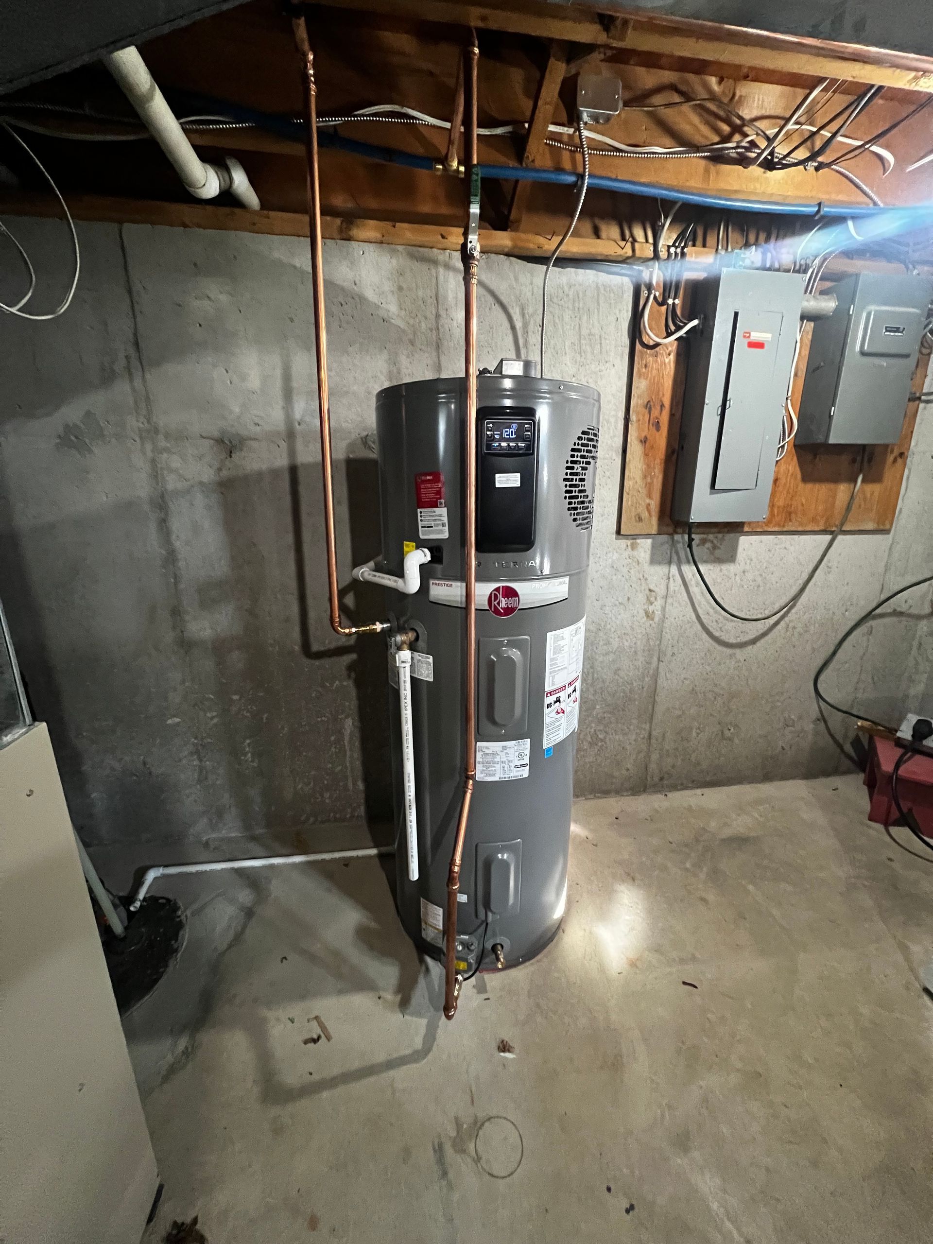 A water heater is hanging from the ceiling in a basement.