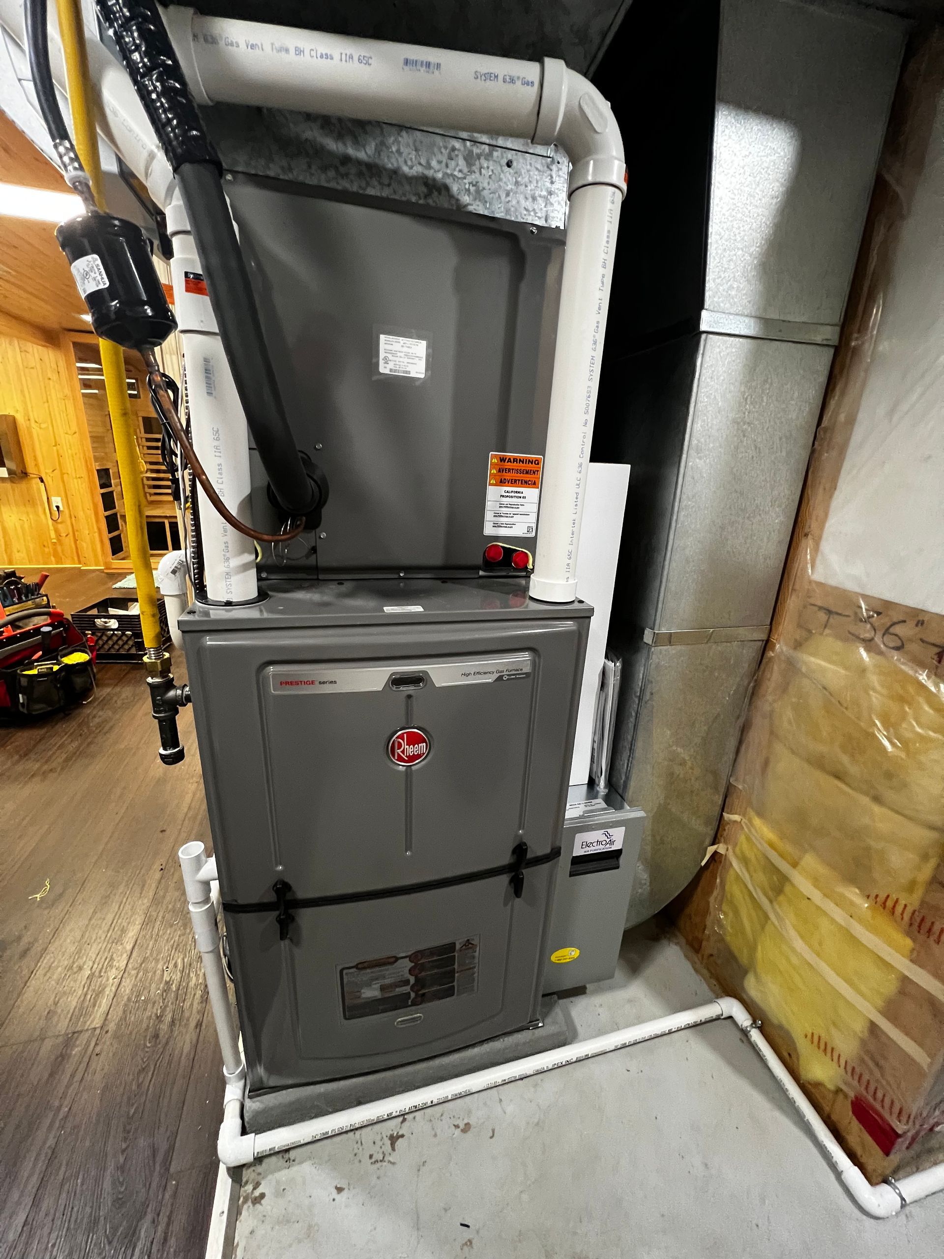 A furnace is sitting in a basement next to a ladder.