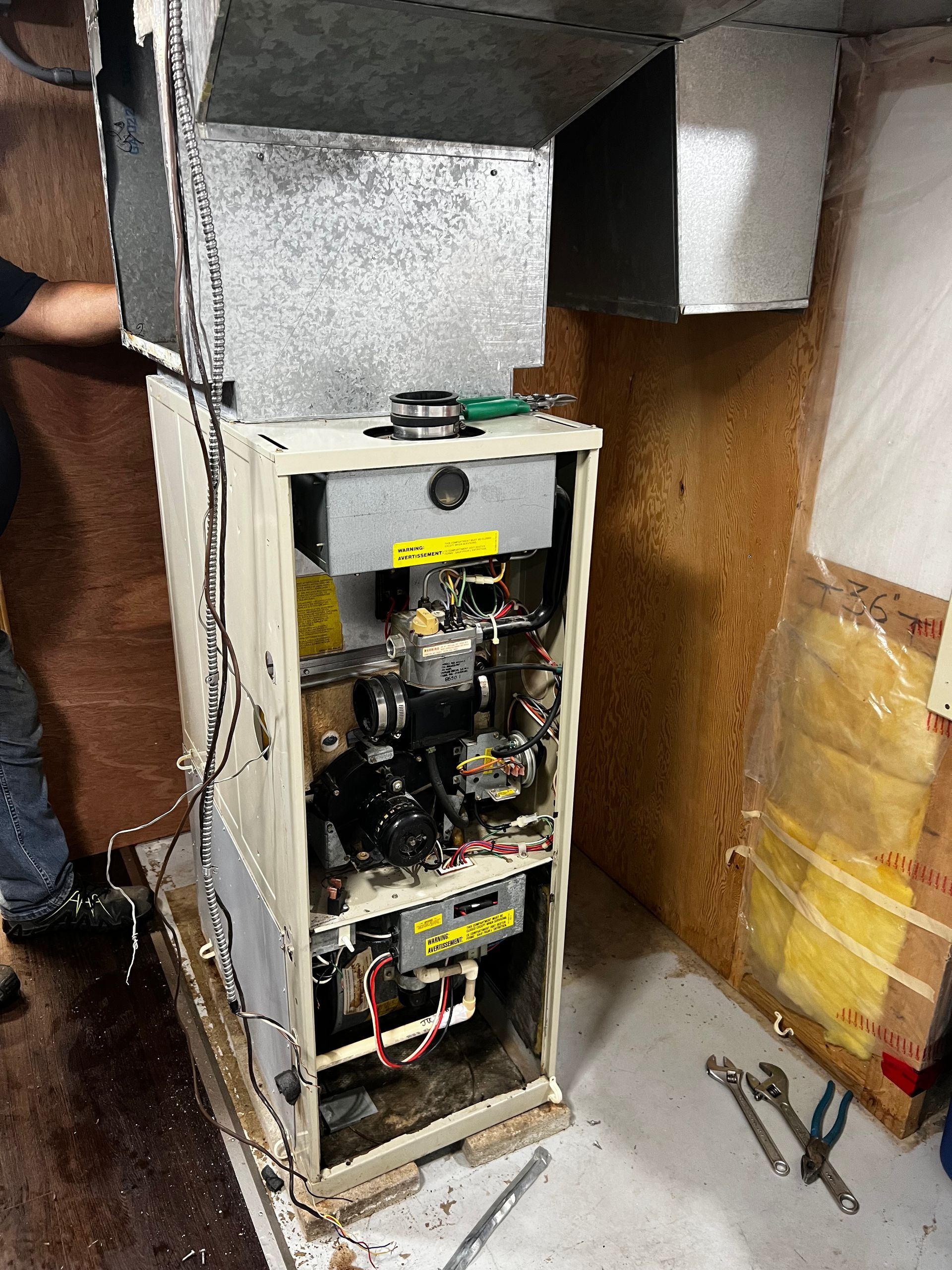 A man is working on a furnace in a basement.