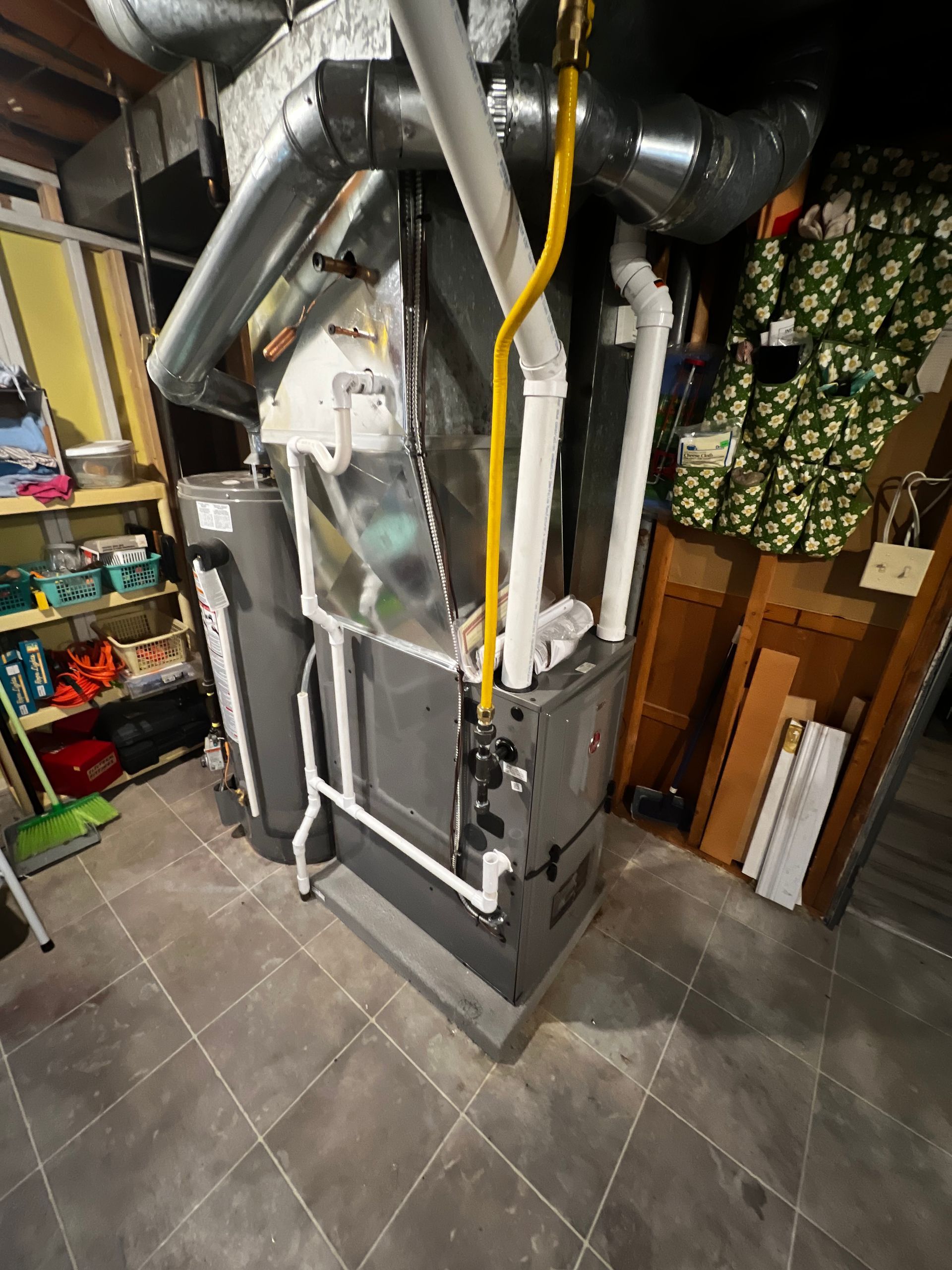 A boiler is sitting in the corner of a room in a basement.