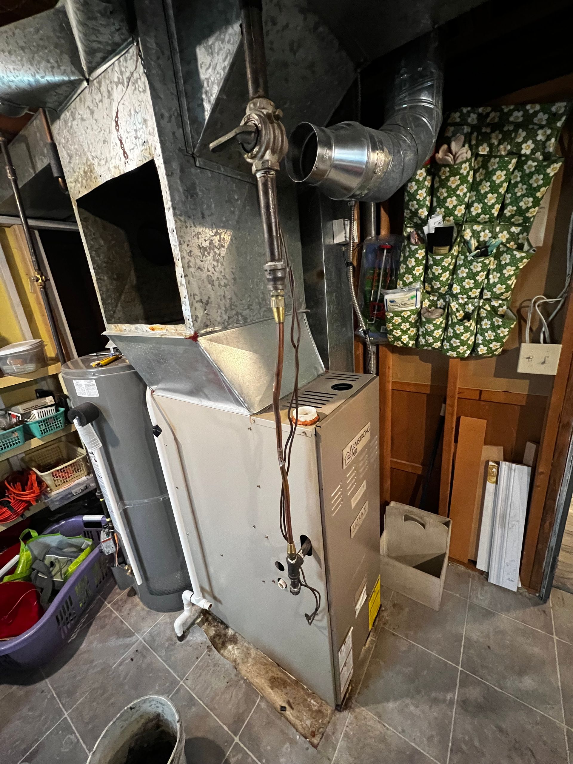 A furnace is sitting in the corner of a room in a basement.