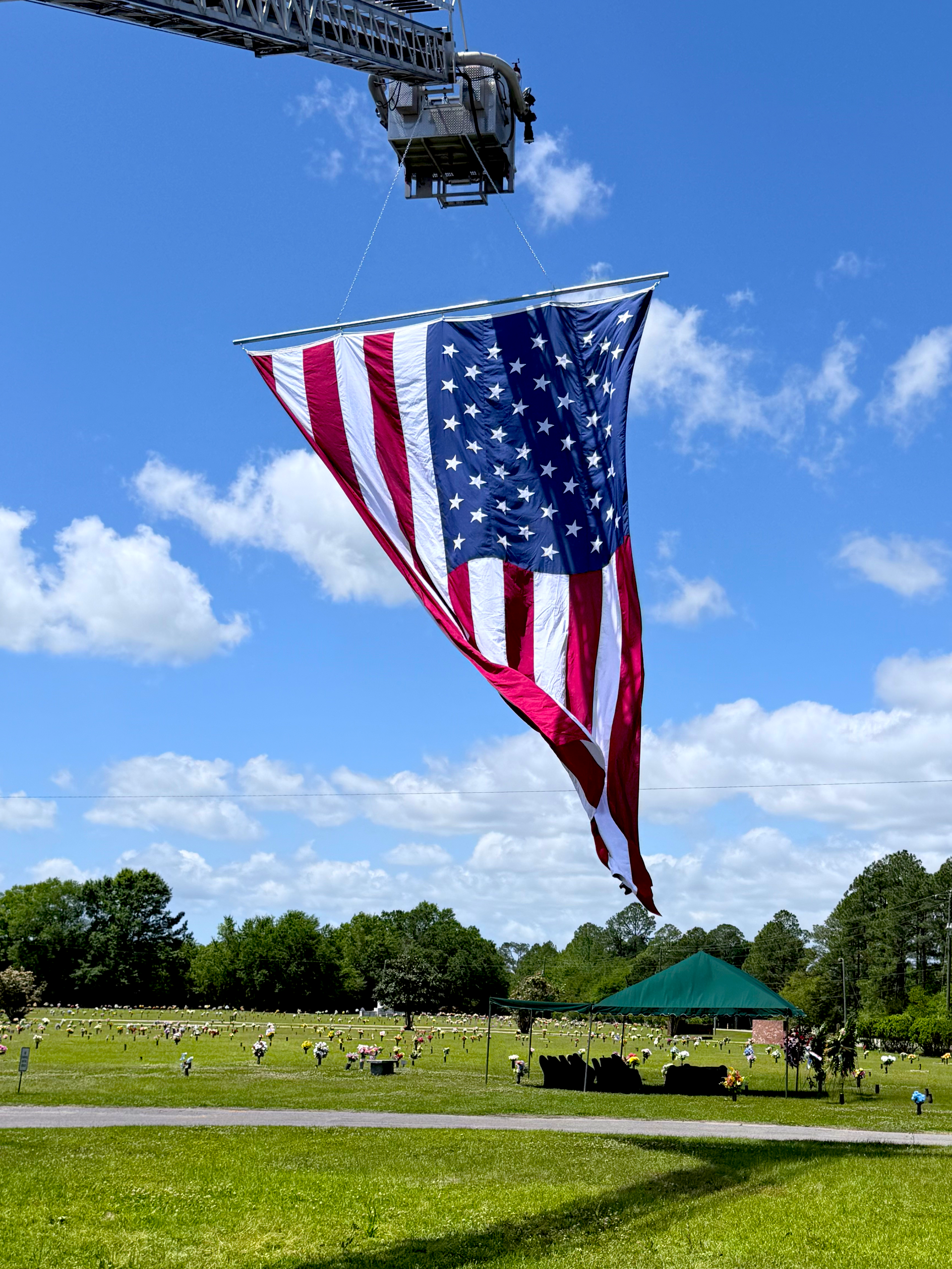 USA flag flown from fire engine honoring a firefighter at graveside with a unique USA flag raising.