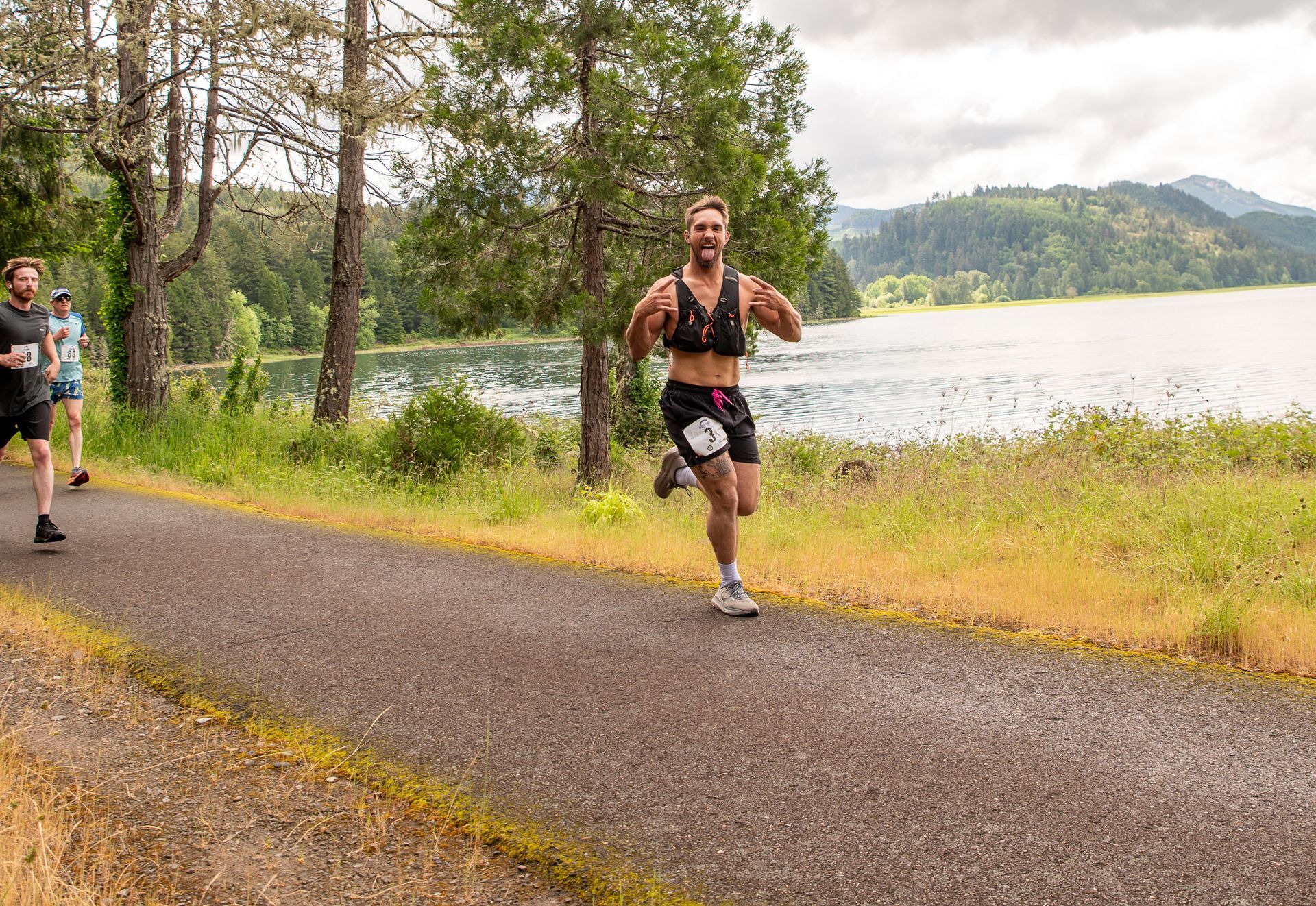 A man is running on a bridge with the number 211 on his shirt.