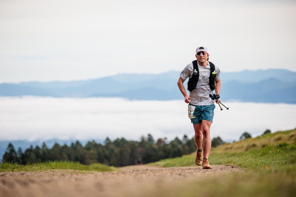 A man is running on a dirt road in the mountains.