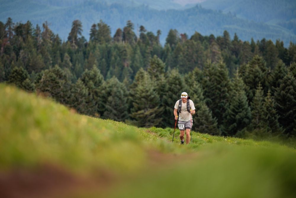 A woman is running down a dirt path in the woods.