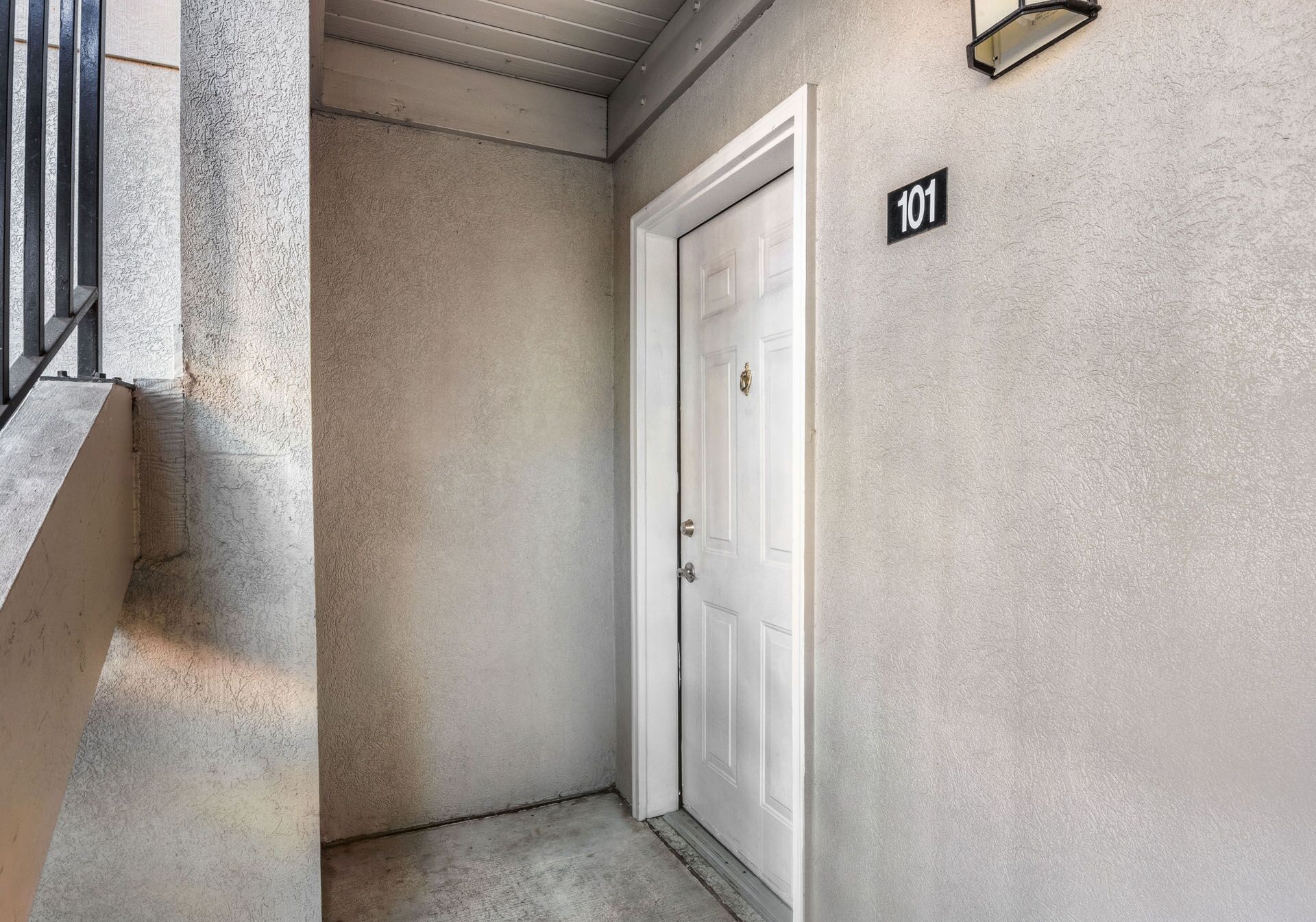 Apartment hallway with a white door labeled 101 and a wall light.