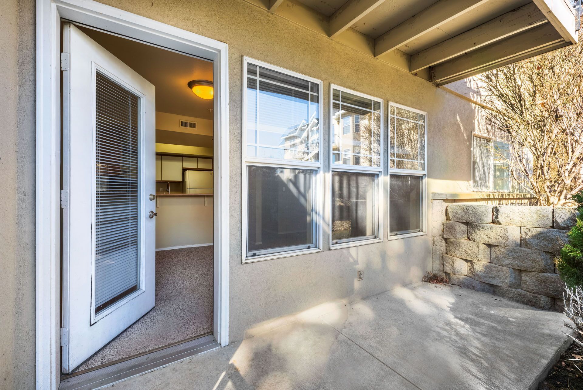 Open front door with screen, windows, and stone walkway beside a beige house.