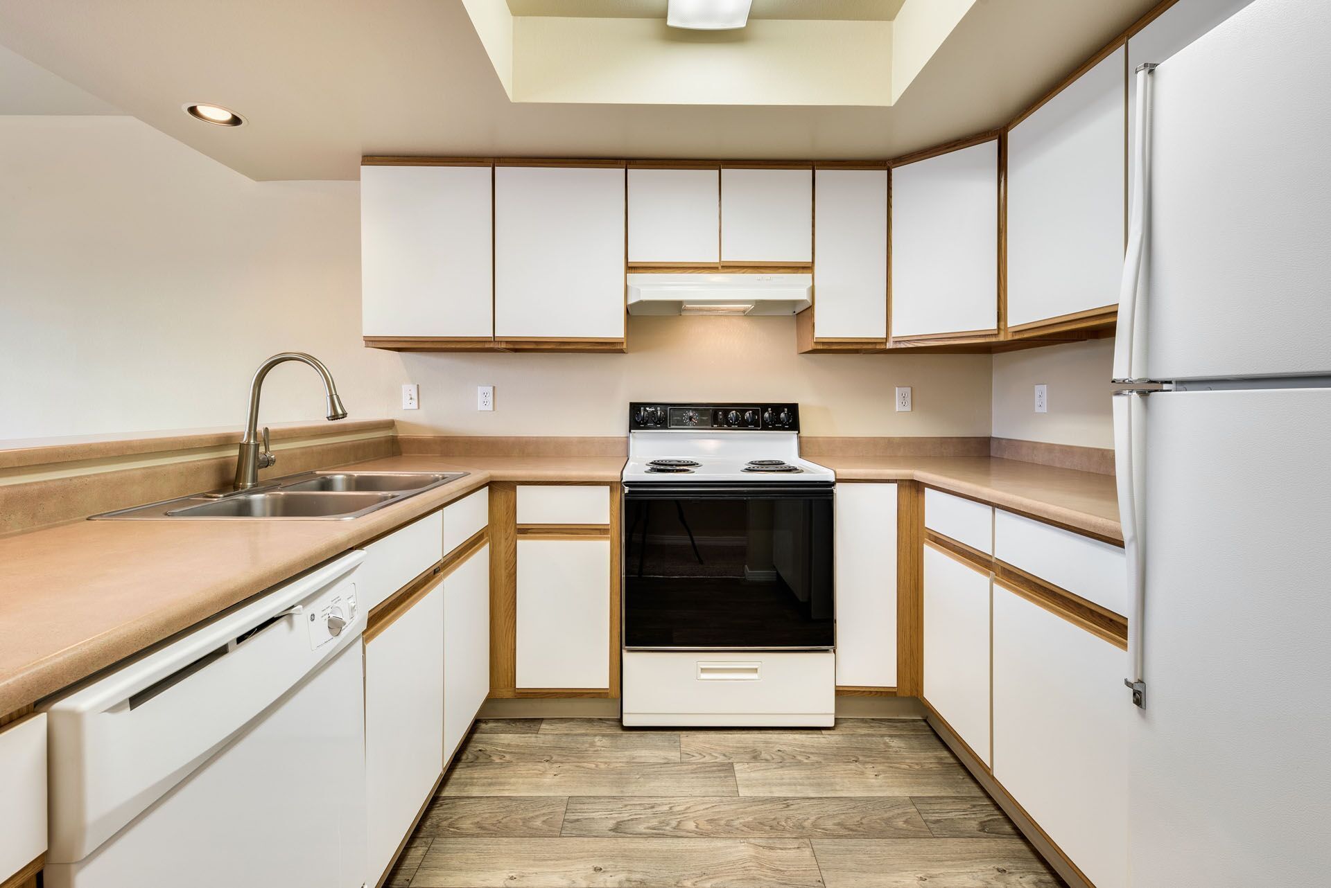 Bright white kitchen with wood countertops, white cabinets, stove, sink, and refrigerator.