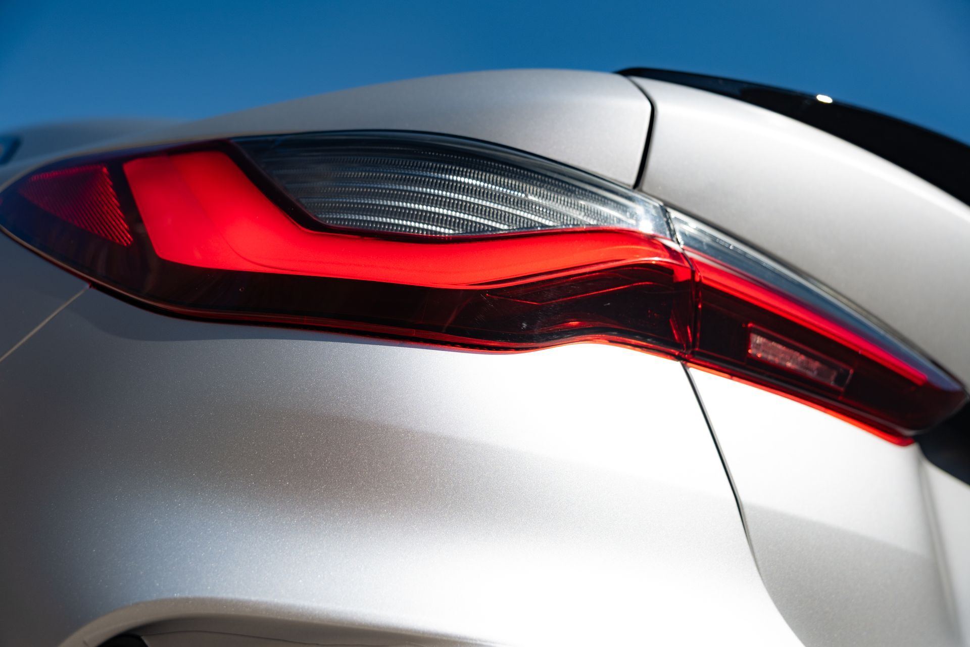 Close-up of a silver car’s red taillight and rear body panel