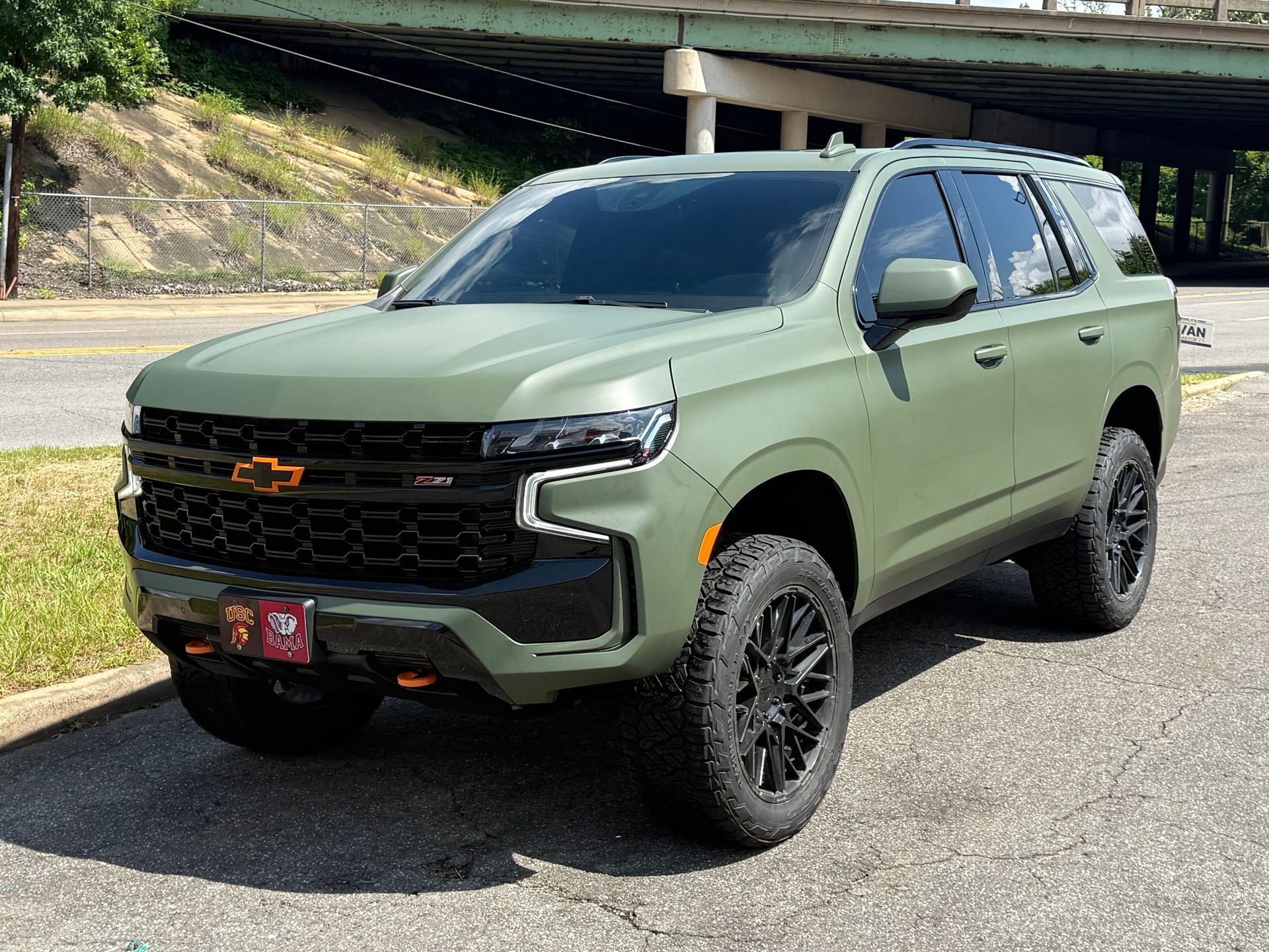 Olive green lifted SUV parked outdoors under an overpass.