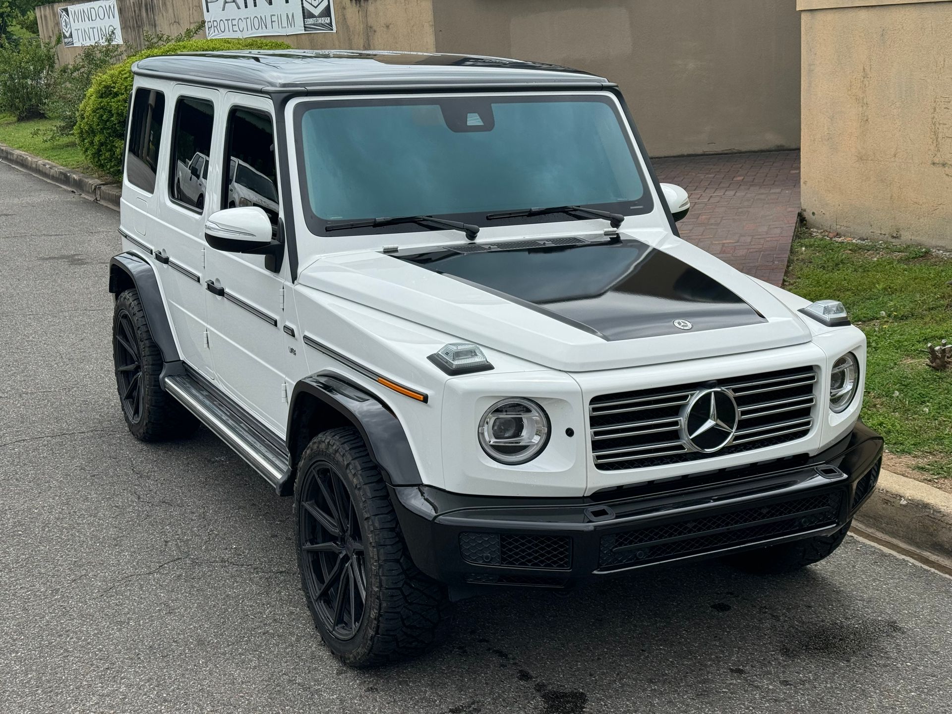 White Mercedes G-Class SUV parked on a street, with black trim and dark wheels.