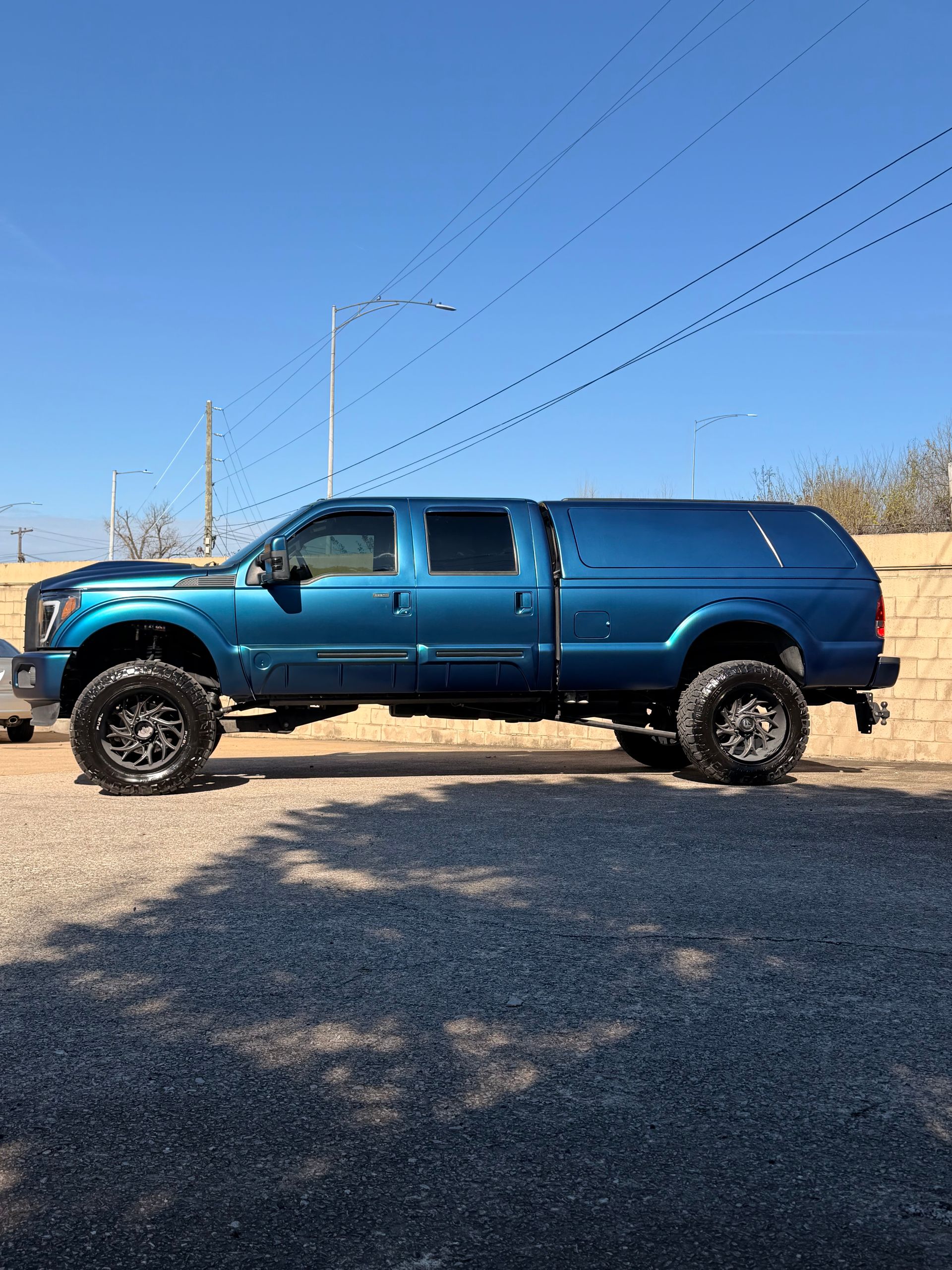 Blue lifted pickup truck parked on a gravel road under a clear sky