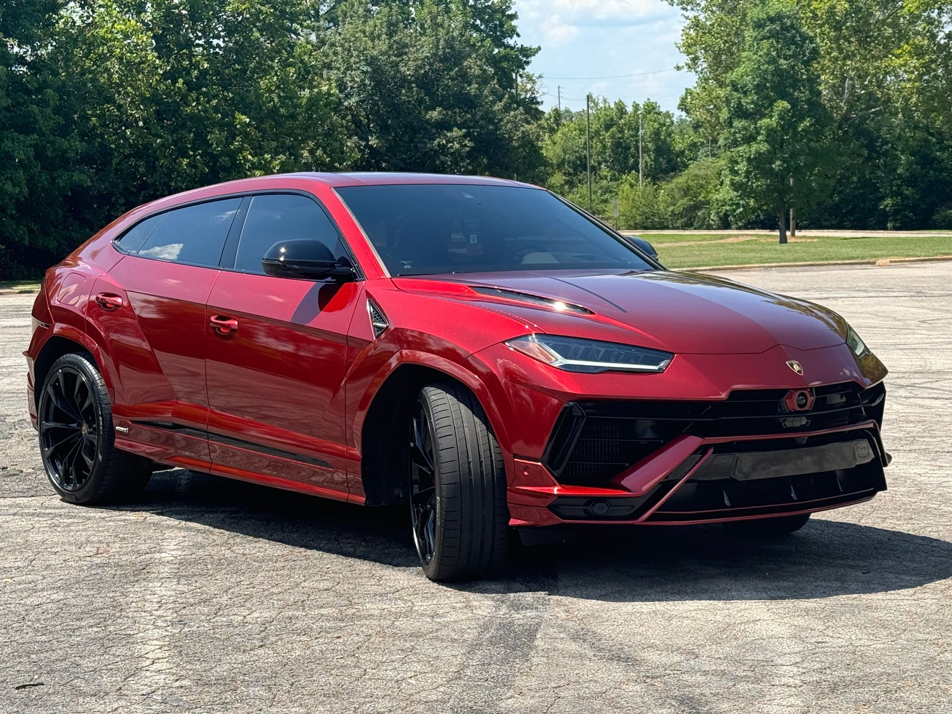 Red sports SUV parked on pavement, shown in front view under a sunny sky.
