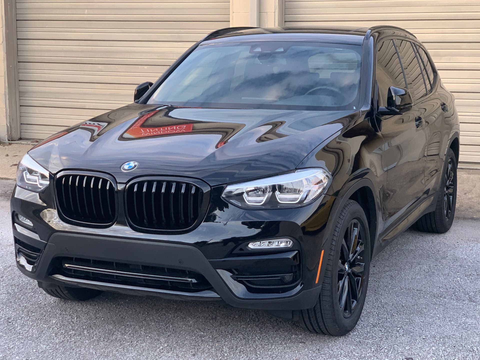 Black BMW SUV parked in front of a beige garage door