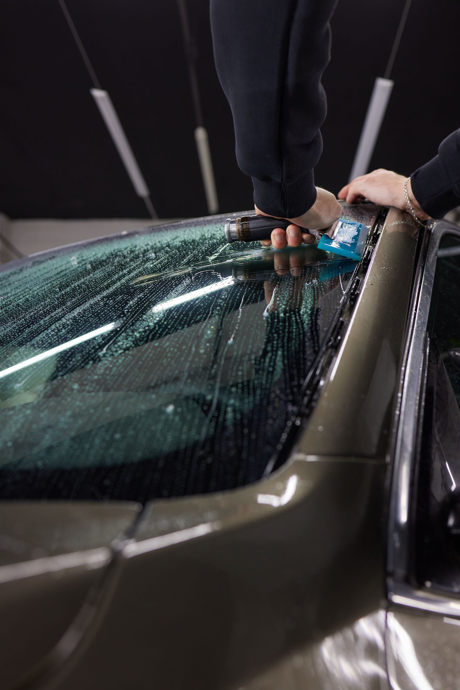 Person applying windshield film to a car in a dark garage