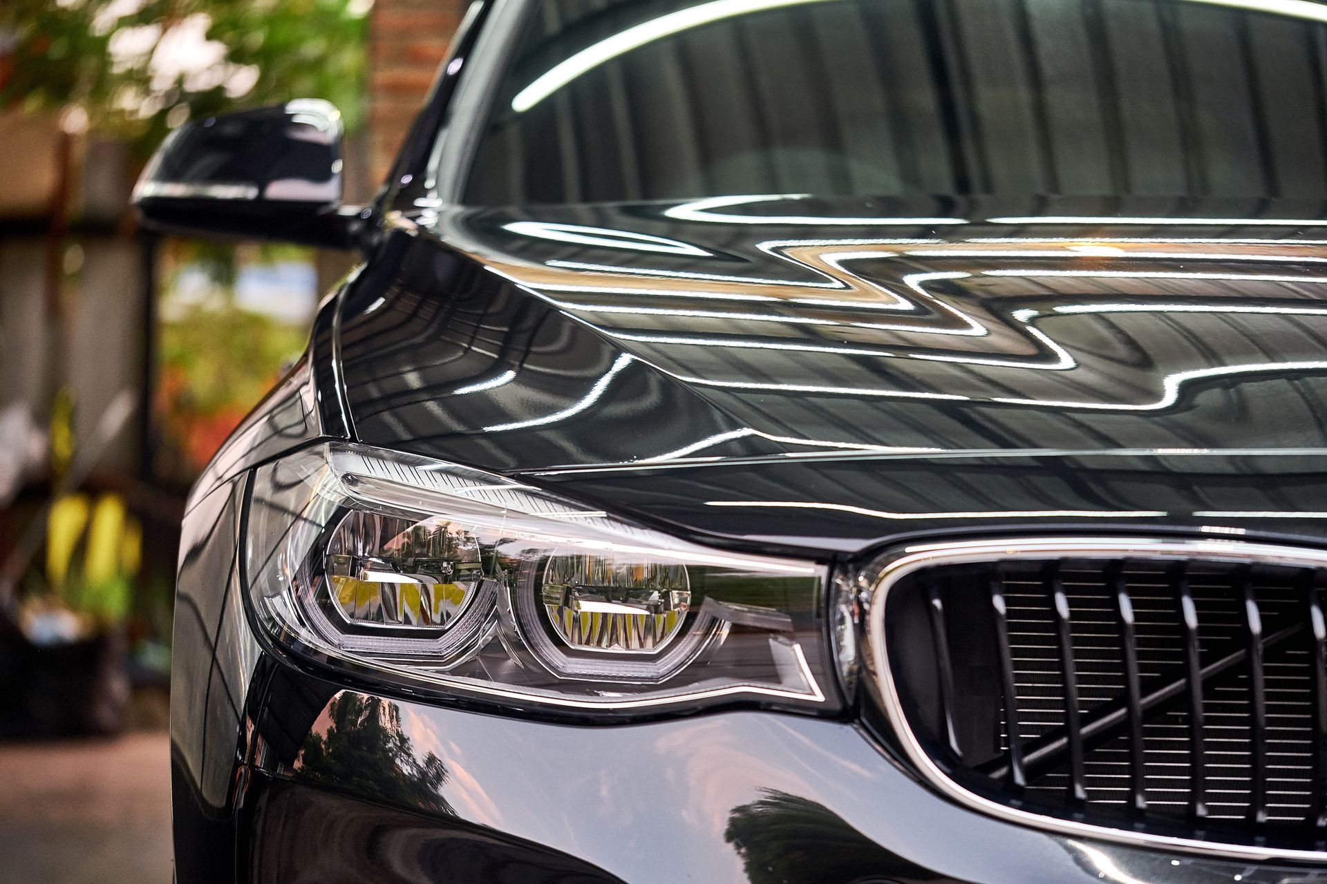 Close-up of a black BMW front grille and headlight in a showroom setting