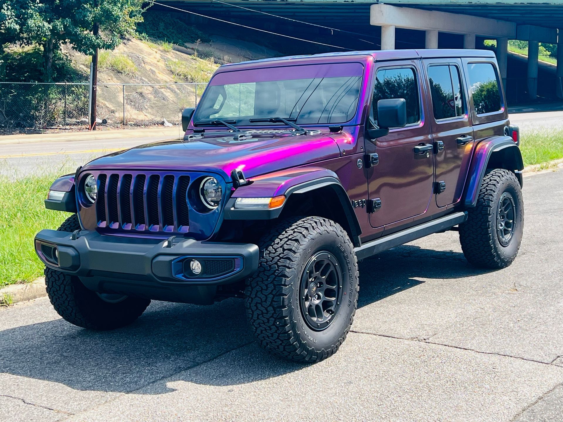 Purple Jeep Wrangler parked on a road in daylight, with off-road tires and black trim