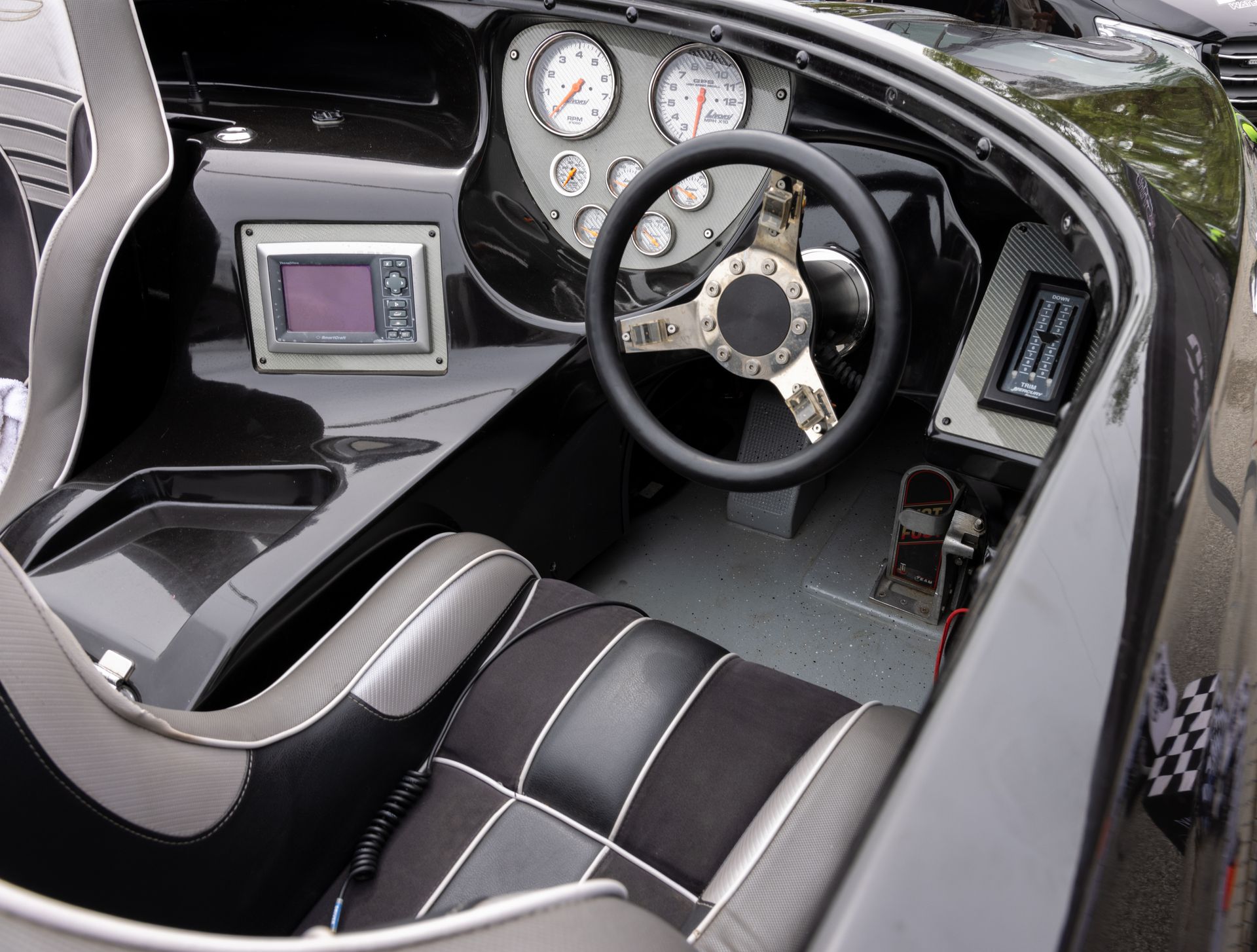 Sporty boat cockpit with black seats, steering wheel, gauges, and two mounted screens