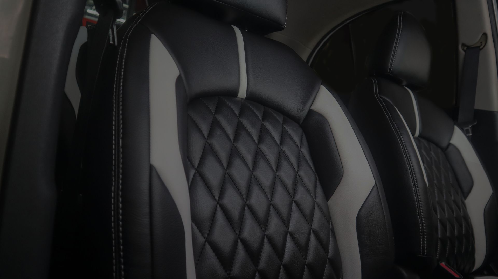 Black-and-gray quilted leather car seats with white stitching, viewed from inside the vehicle