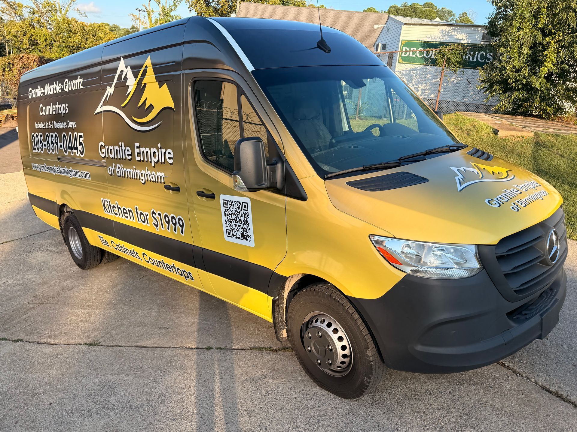Yellow and black service van with mountain logo parked on a driveway in daylight