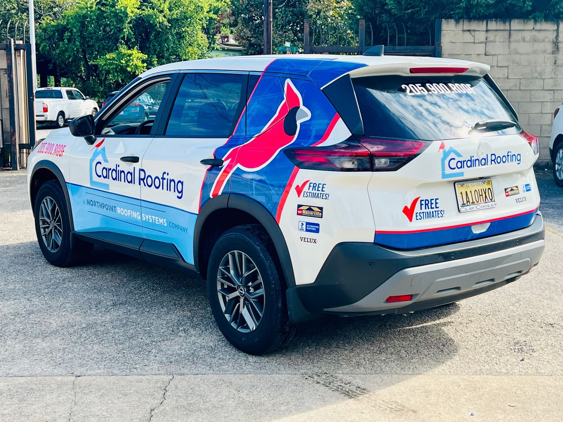 Branded white SUV with blue and pink graphics and “Cortina Roofing” parked outdoors on pavement