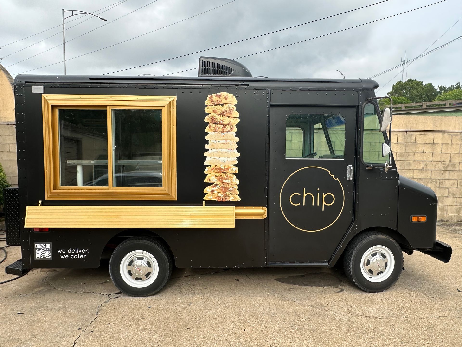 Black food truck with gold trim and “chip” logo parked outdoors under cloudy sky