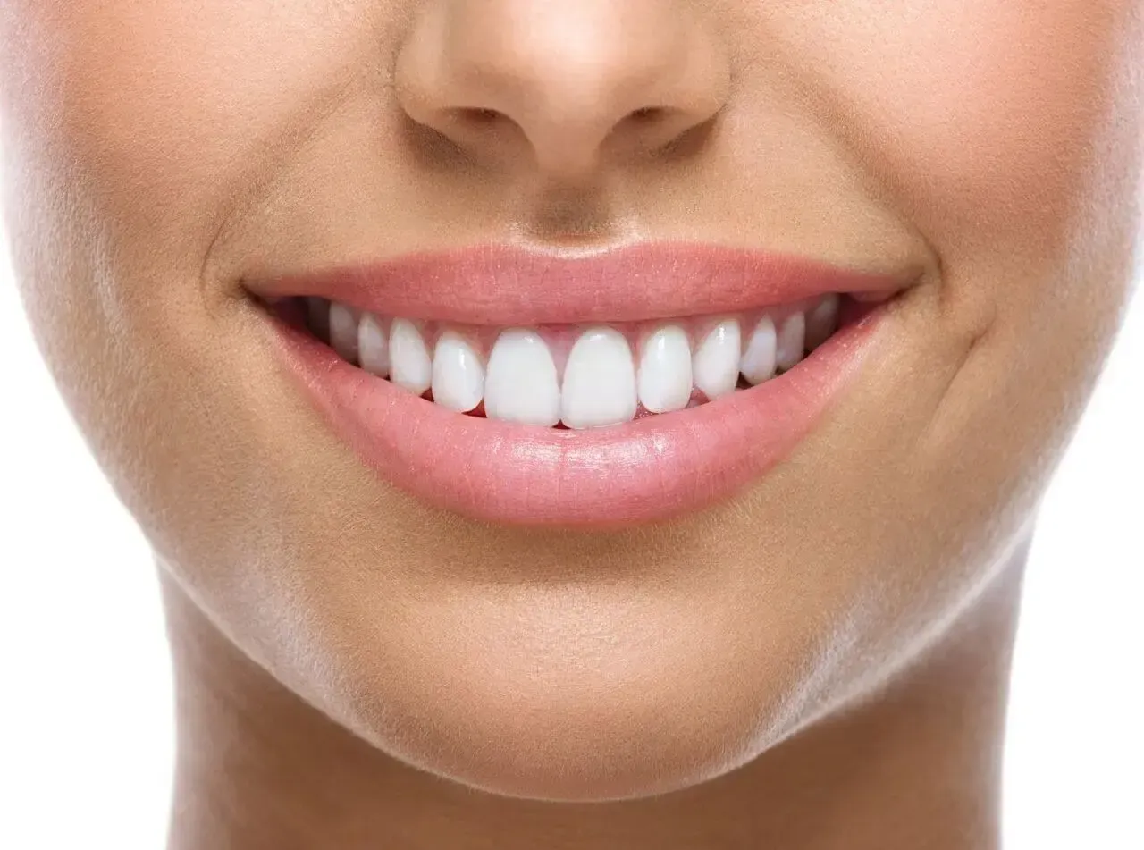A close up of a woman 's smile with white teeth and pink lips.