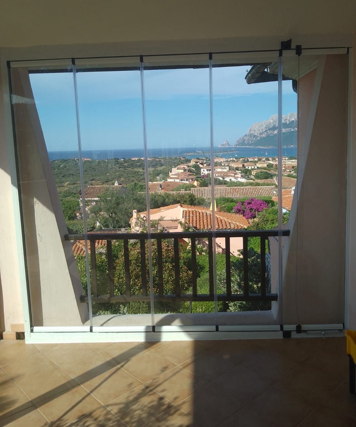 Le vetrate incorniciano una vista panoramica sulla città, sull'oceano e sul cielo. Le pareti beige fiancheggiano le finestre.