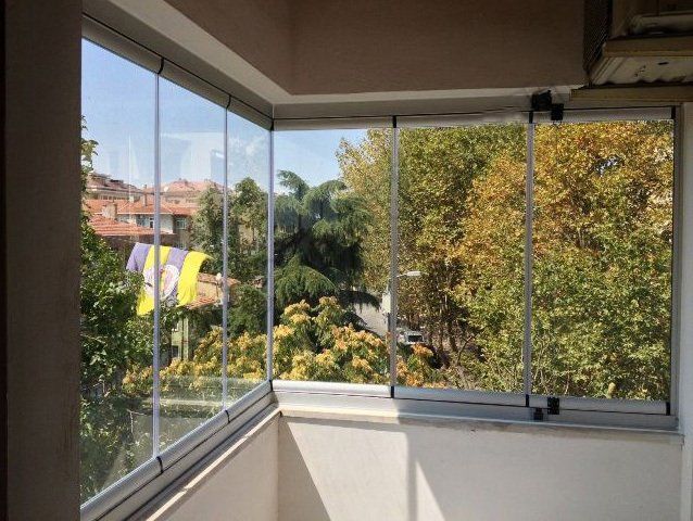 Balcone con vetrate e vista su alberi, edifici e una bandiera gialla e viola.