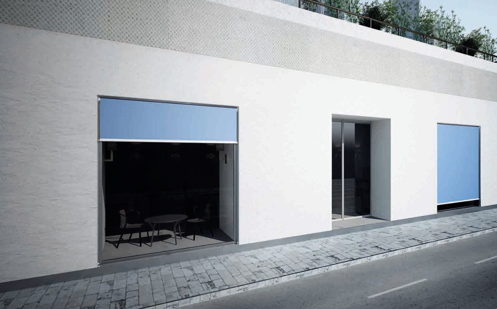 Edificio bianco con porte da garage blu aperte e chiuse, porta in vetro e strada acciottolata.