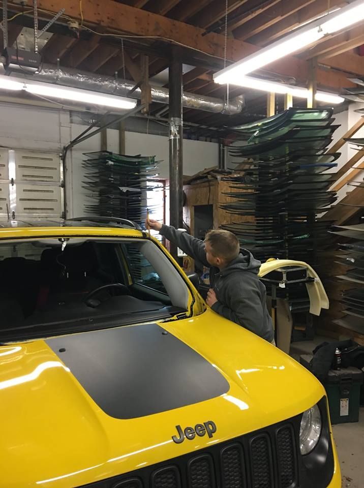 A man is working on a yellow jeep in a garage.