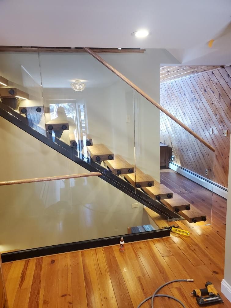 A staircase with a glass railing and wooden steps in a house.