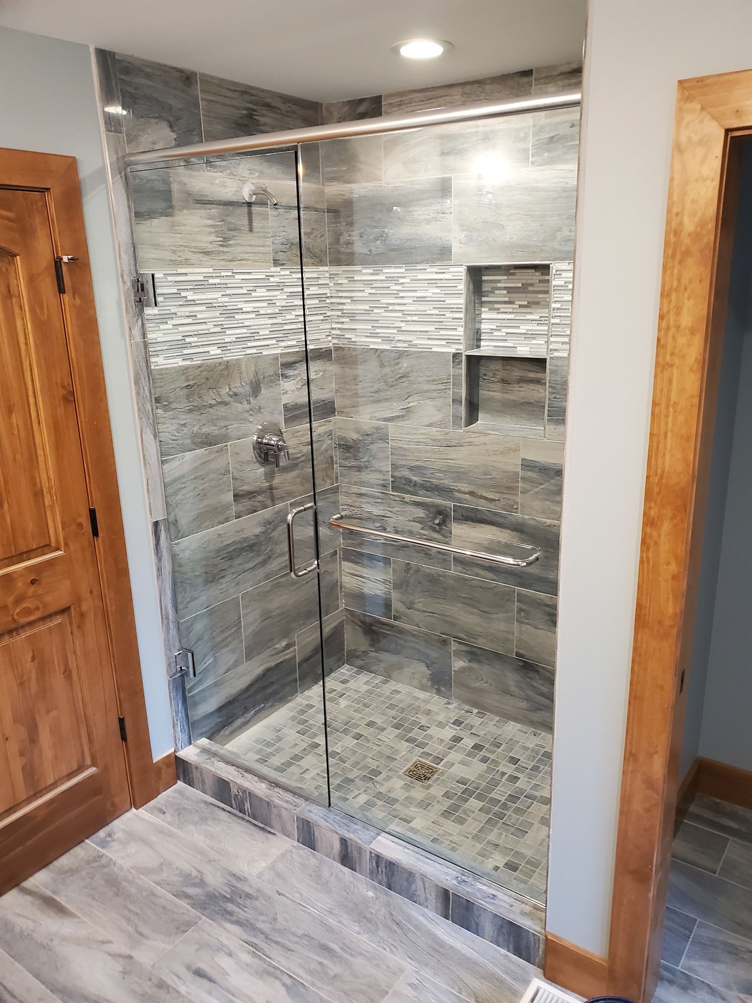 A bathroom with a walk in shower with a glass door.