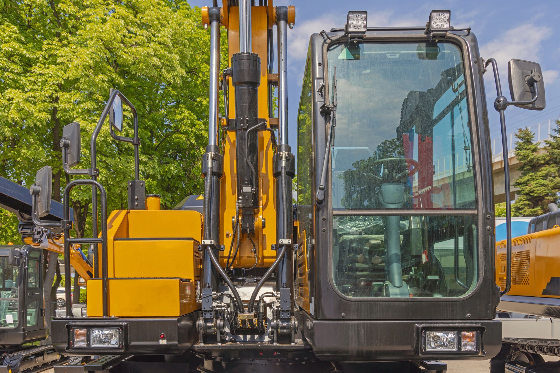 Heavy equipment glass on a yellow excavator cab with a clear front windshield
