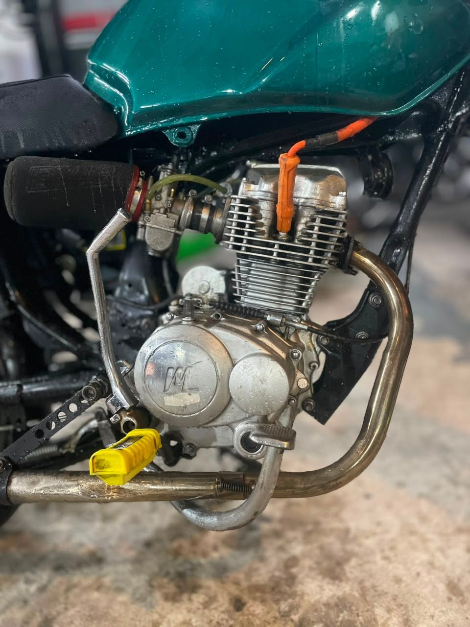 Primer plano del motor y el tubo de escape de una motocicleta verde debajo del depósito de combustible.