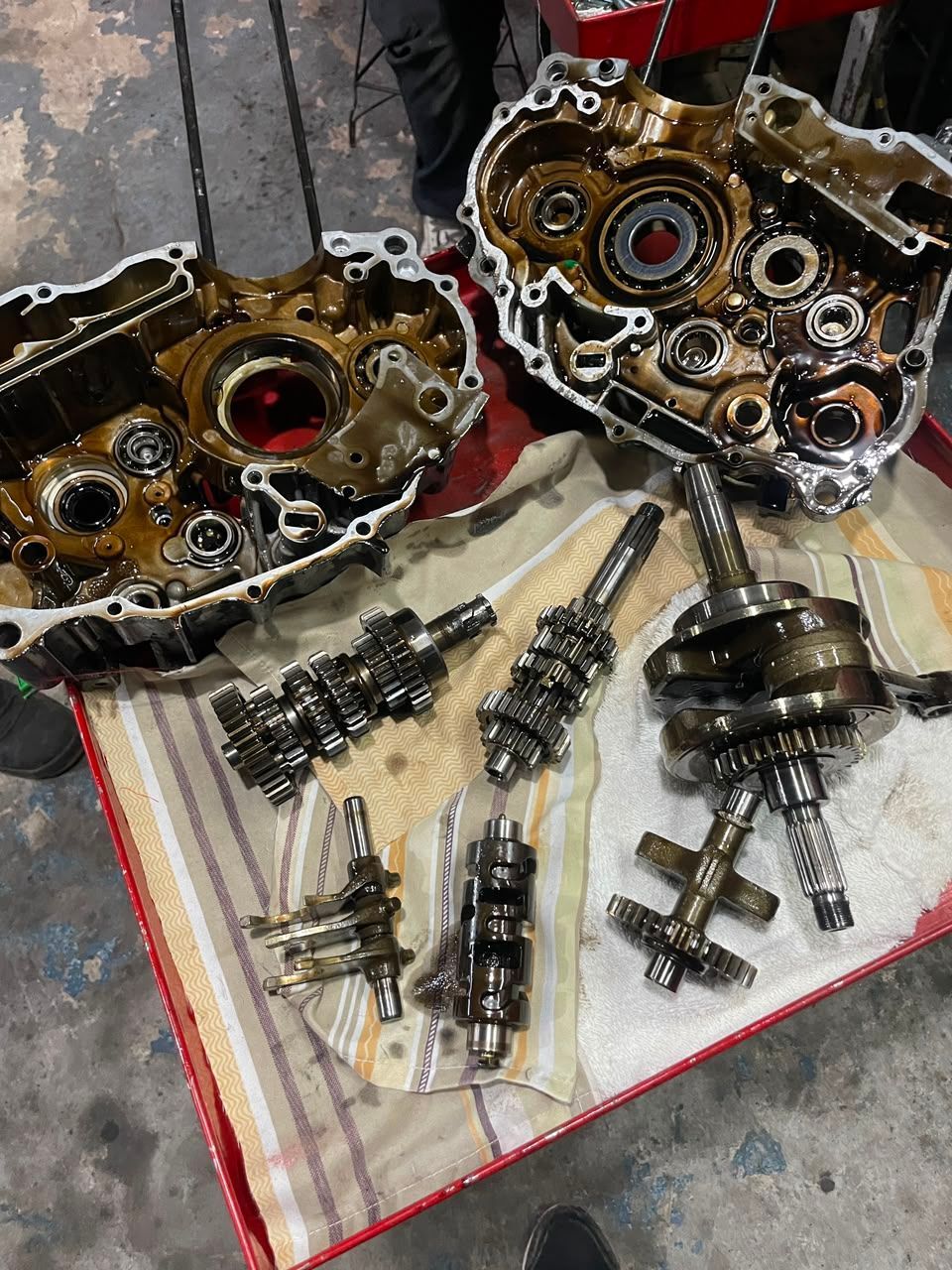 Piezas de motor y engranajes desmontados extendidos sobre una tela en el suelo del taller.