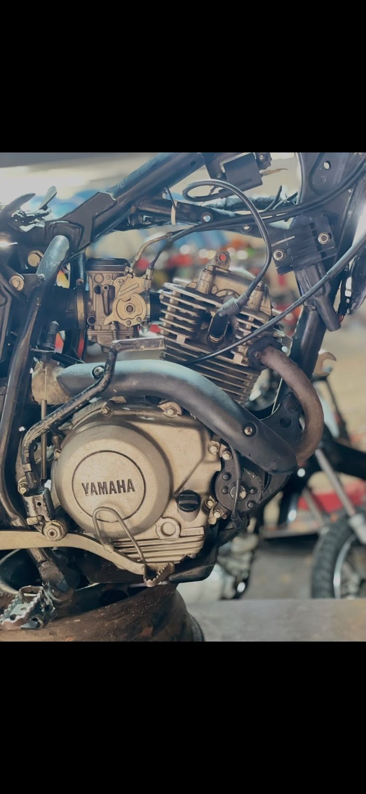 Primer plano del motor de una motocicleta Yamaha con el chasis y el cableado a la vista en un taller.