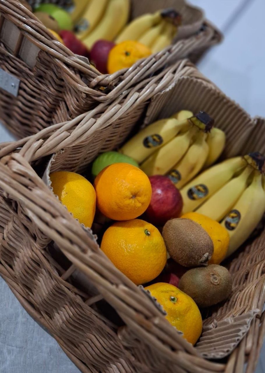 Cestas de mimbre llenas de diversas frutas, incluidos plátanos, naranjas, manzanas, kiwis y mangos.