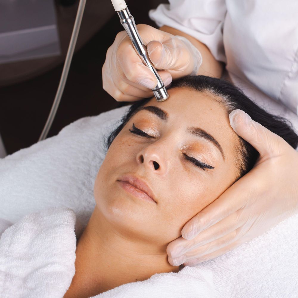 Microdermabrasion handpiece and infusion serums laid out before a treatment