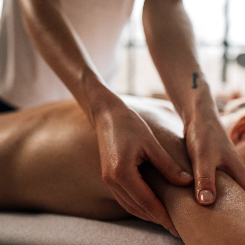 Light rhythmic lymphatic drainage strokes along the arm during a massage therapy session