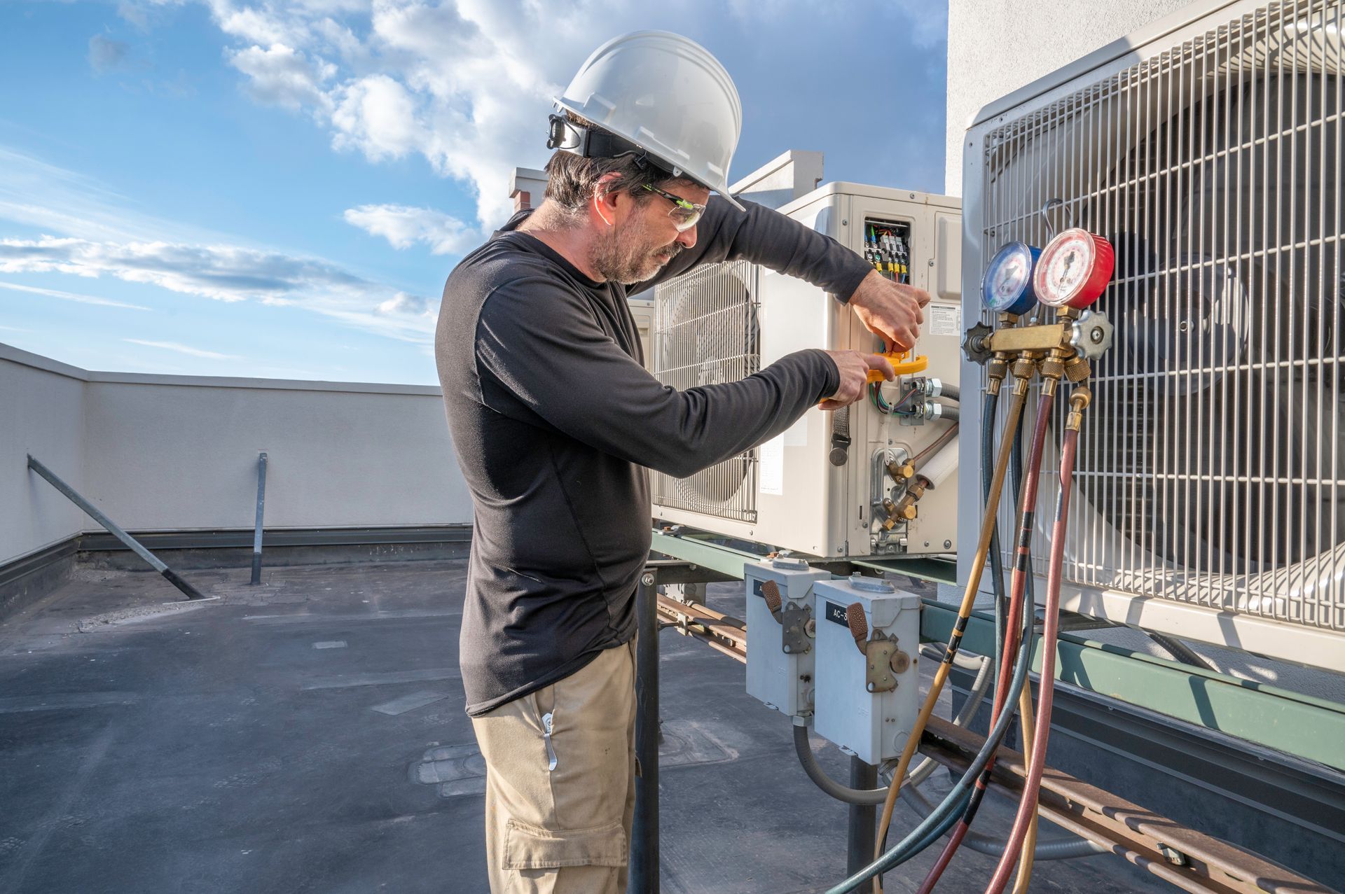 Un uomo sta lavorando su un condizionatore d'aria sul tetto di un edificio.