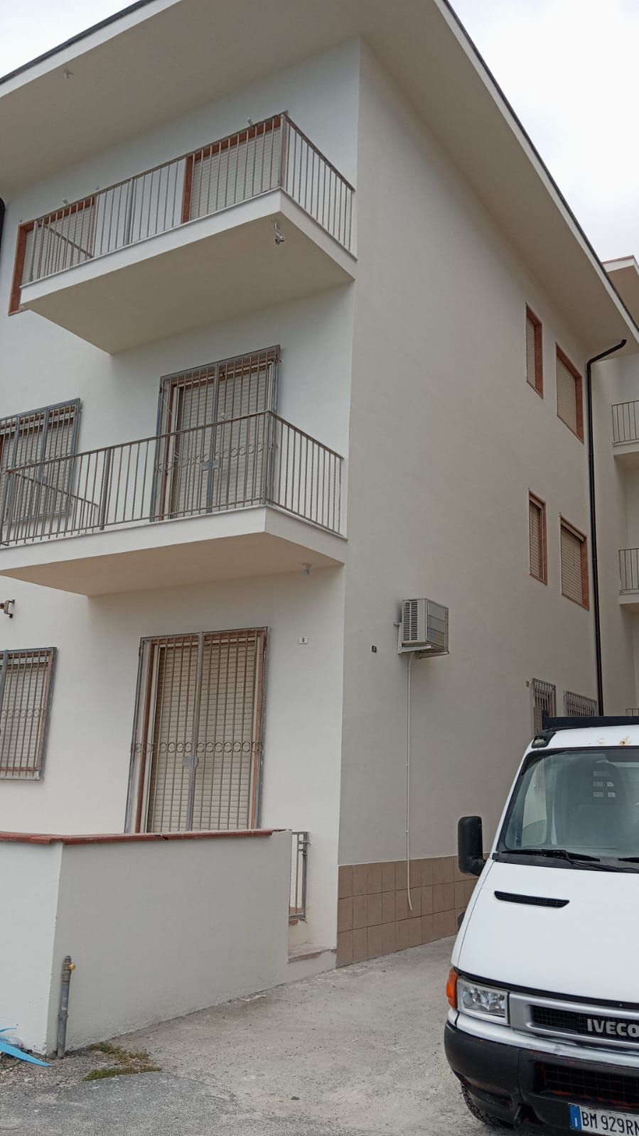 Un furgone bianco è parcheggiato davanti a un grande edificio bianco.
