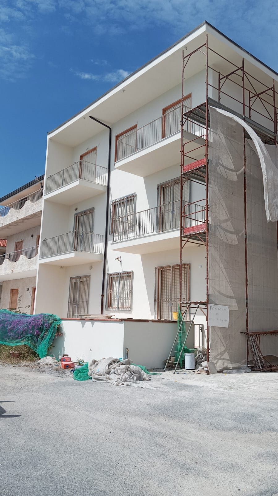 Un edificio in costruzione circondato da impalcature e con un cielo azzurro sullo sfondo.